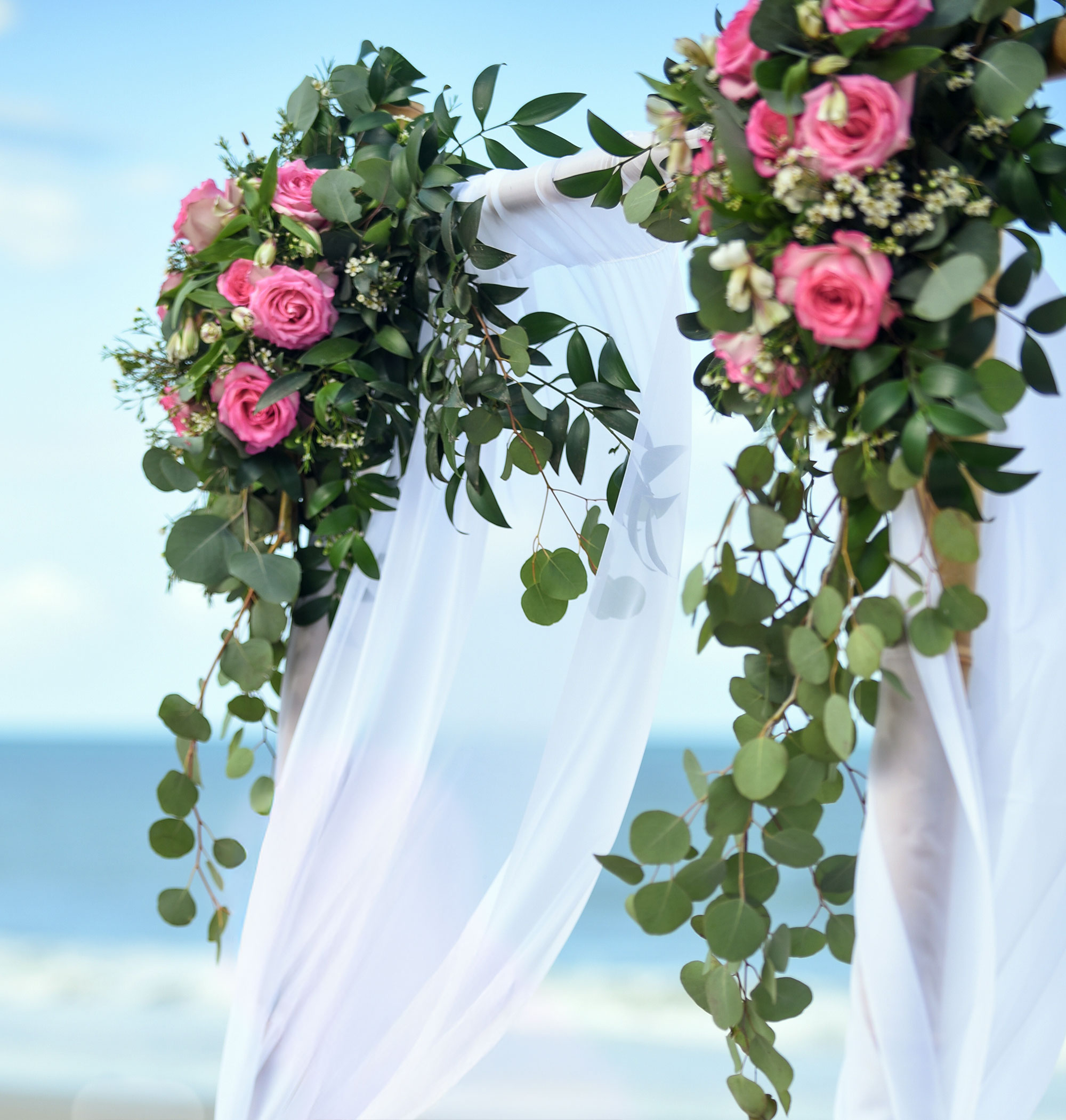 Photo of two wedding arch arrangements with hot pink roses and lots of greenery
